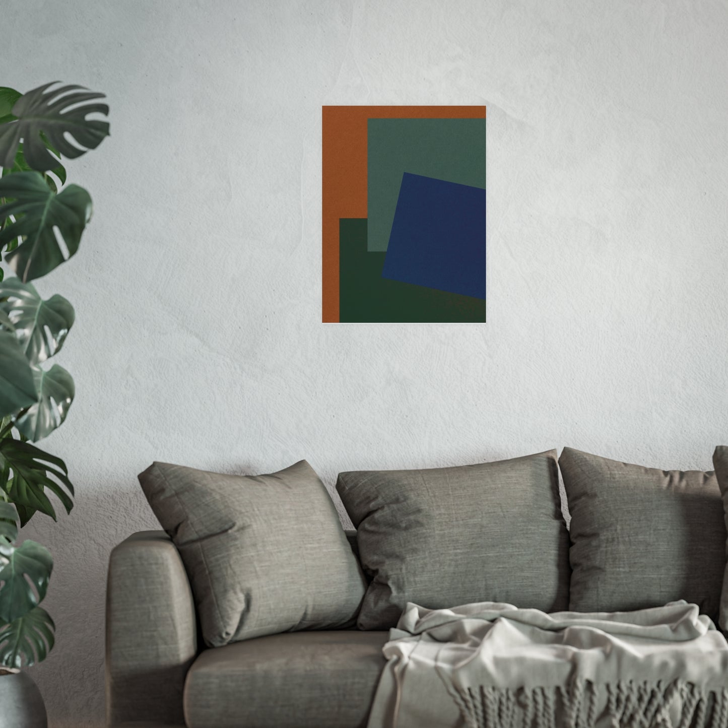Abstract art piece on a wall above a sofa with a plant to the left.
