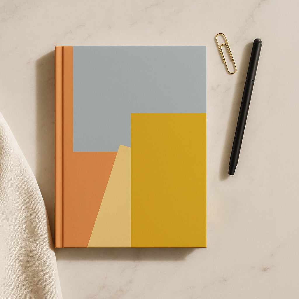 Notebook with geometric design on a beige surface with a pen and paper clip.