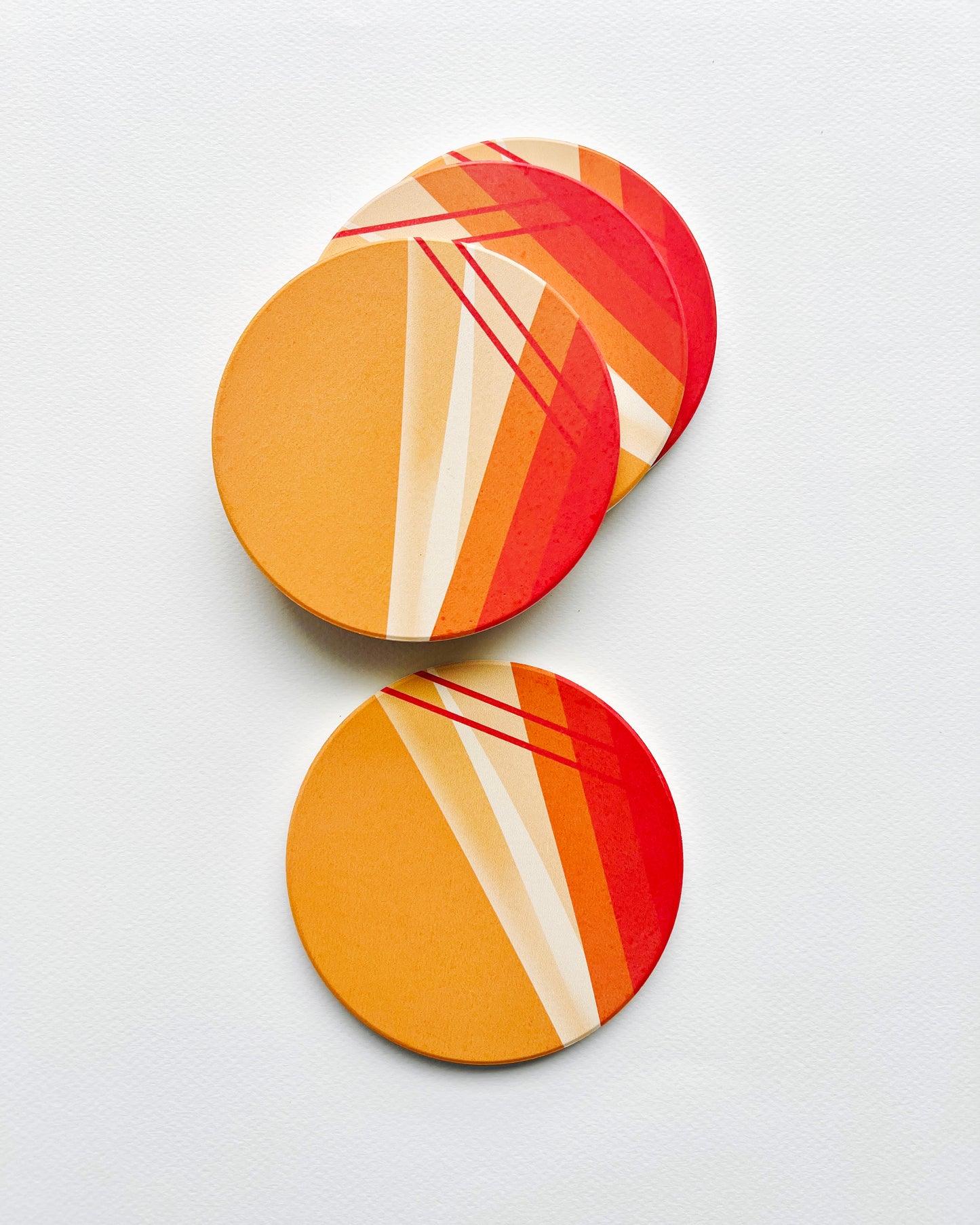 Two round coasters with a colorful abstract design on a white background
