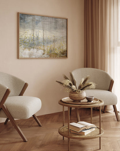 Modern living room with two beige armchairs, a wooden side table, and abstract art on the wall.