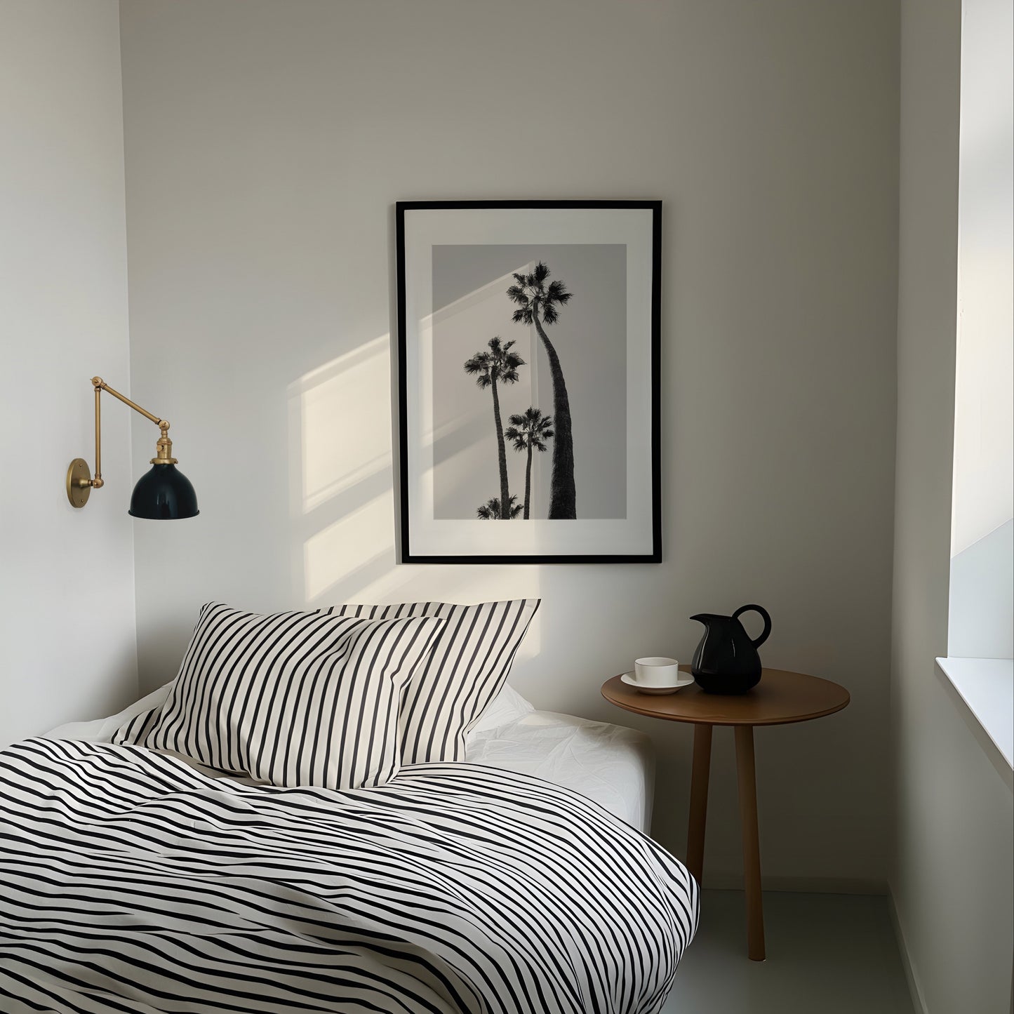 Modern bedroom with striped bedding, side table, and wall art.