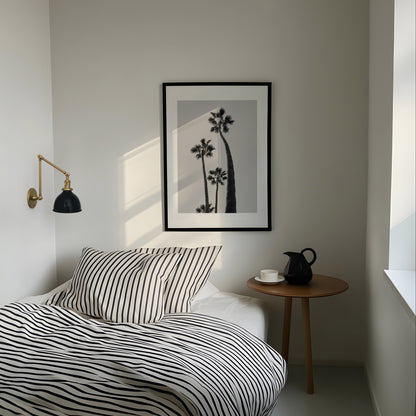 Modern bedroom with striped bedding, side table, and wall art.